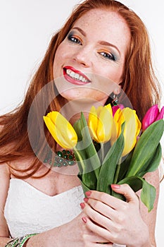 Beautiful redheaded happy girl is holding tulips
