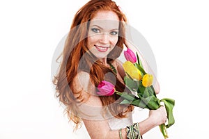 Beautiful redheaded smiling girl is holding tulips