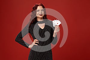 Beautiful redheaded woman is holding some playing cards. Casino