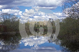 Beautiful reflection of the sky with clouds and trees in the water. Landscapes of nature