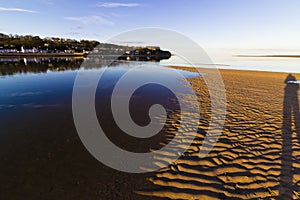 Beautiful reflection of the small village of Red Wharf Bay on the surface of the incoming tide, Isle of Anglesey, North Wales