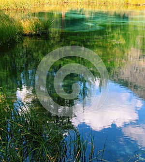 Beautiful reflection of trees and clouds in a quiet smooth surface of lake