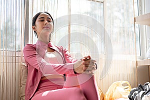 A beautiful and relaxed Asian woman is resting, sitting with her eyes closed on a comfortable couch