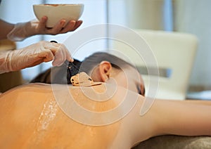 Beautiful relaxed woman having clay body mask