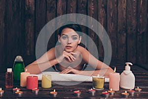 Beautiful relaxed young woman laying in spa salon with candles a