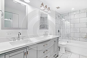 A beautiful remodeled bathroom with grey cabinet and white counter top.