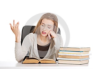 Beautiful resigned student woman with stack of books.