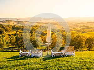 Beautiful rest place with umbrellas and sunbeds in Tuscan landscape. Evening summer sunset. Italy