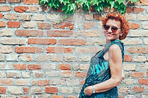 Beautiful retro older woman in front of the brick wall