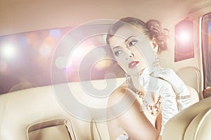 Beautiful and rich superstar girl sitting in a retro car photo