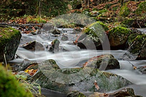 Beautiful river embedded in rocks flows down the mountain. The stones are covered with moss