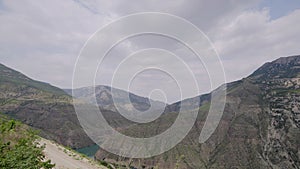 Beautiful river in rocky mountains on background of cloudy sky. Action. Turquoise river among rocky mountains in cloudy