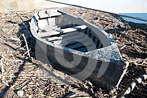 An ancient drifting boat surrounded by debris after the flood of the river photo