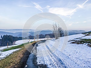 Beautiful road with melting snow in a countryside nature landscape with view over the mountains in Germany Hochsauerland