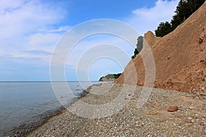 Beautiful rocky beach with calm waters and cliffs with sunny skies overhead, Chimney Bluffs, NY, summer 2022 photo