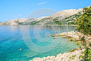 Beautiful rocky beach with crystal clear sea and people snorkeli