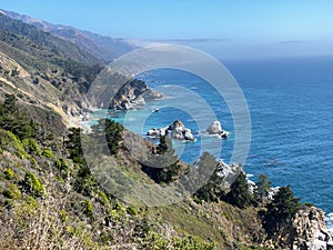 Beautiful rocky California coastline with Pacific Ocean, mountains and trees