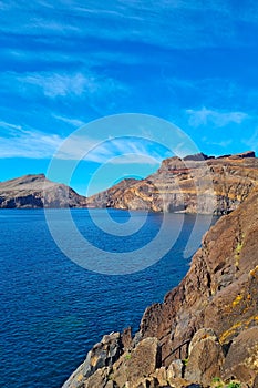 Beautiful rocky coast of Madeira island, Portugal. Vacation on the island. Red earth and mountains.