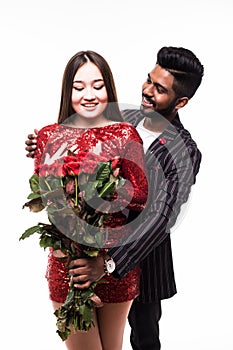 Beautiful romantic asian couple, attractive young woman in dress holding red roses and handsome man in suit are in love isolated