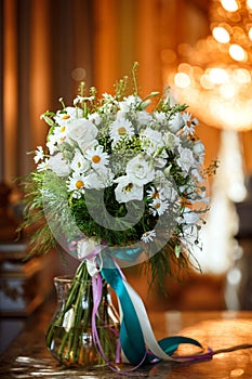 Beautiful romantic bouquet of white flowers with chamomiles in luxury interior