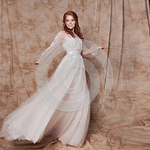 Beautiful and romantic bride in wedding dress with long sleeves. Young redheaded woman in wedding dress