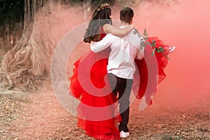 Beautiful romantic couple Attractive young woman in red dress and crown with handsome man in white shirt are dancing on