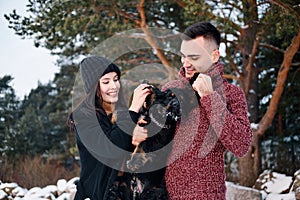 Beautiful romantic couple is having fun with their dog outdoors in winter day