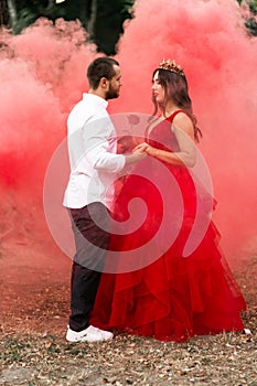 Beautiful romantic couple kiss closeup. Attractive young woman in red dress and crown with handsome man in white shirt