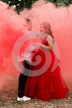 Beautiful romantic couple kiss closeup. Attractive young woman in red dress and crown with handsome man in white shirt