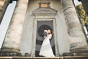 Beautiful romantic couple of newlyweds bride and groom hugging near old castle