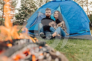 Beautiful romantic couple sitting in tent near the fire and holding hands.