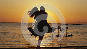 Beautiful romantic man and woman running to each other on the beach, hugging and spin around on amazing sunset. Having