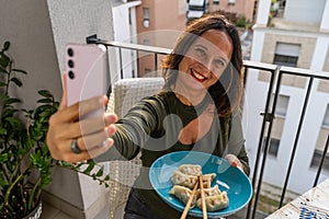 beautiful romantic middle aged woman taking a selfie on the outdoor terrace at sunset