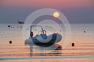 Beautiful romantic ocean sunrise at rimini beach italy; boat and ship in water at golden hour