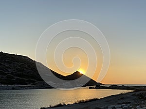 Beautiful romantic sunset on the Aegean Sea with a lighthouse.