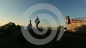 Beautiful romantic wedding couple, groom and bride hugging near old castle on sunset