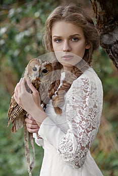 Beautiful romantic woman with an owl. The bird sits on her hand.