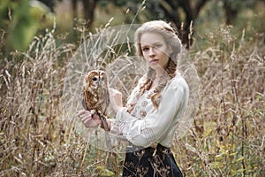 Beautiful romantic woman with an owl. The bird sits on her hand.