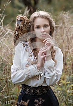 Beautiful romantic woman with an owl. The bird sits on her shoulder.