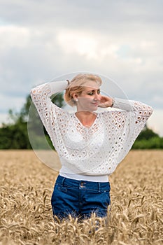 Beautiful romantic woman in white shirt and jeans stand in the golden wheat field. Happy summer or concept