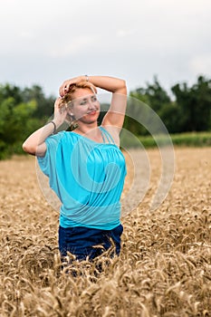 Beautiful romantic woman in white shirt and jeans stand in the golden wheat field. Happy summer concept