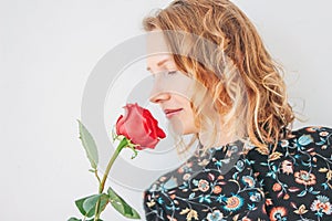 Beautiful romantic young blonde woman in dress with red rose on white background isolated