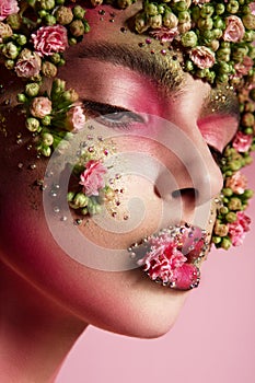 Beautiful romantic young woman with flowers on her face. Inspiration of spring and summer. Perfume, cosmetics concept.