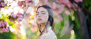 Beautiful romantic young woman posing on a background of blossom cherry tree. Inspiration of spring and summer. Banner