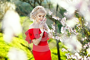 Beautiful romantic young woman in a wreath of flowers posing on a background of flowers. Inspiration of spring and