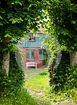 Beautiful and romantical entrance and garden of an old german farmhouse with framework and blooming plants