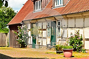 Beautiful and romantical entrance and garden of an old german farmhouse with framework and blooming plants