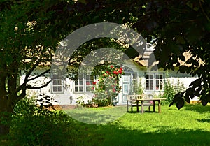 Beautiful and romantical entrance and garden of an old german farmhouse with framework and blooming plants