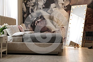 Room interior with large bed, mirror and floral pattern on wall