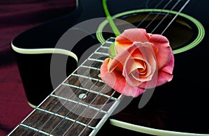 beautiful rose and black acoustic guitar. Symbols of love.